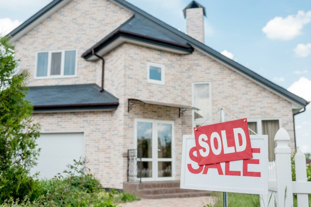 a large brick house with a sold sign standing in the yard